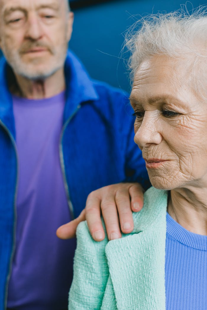 An elderly couple sharing a tender moment indoors. Senior man comforting woman with a gentle touch.